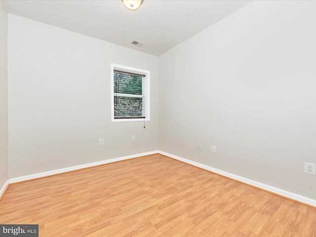 spare room with light wood-type flooring, visible vents, and baseboards