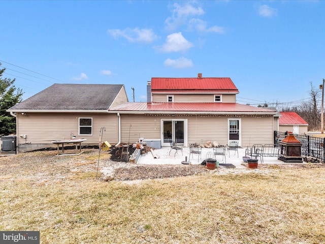 rear view of property with a lawn, metal roof, fence, cooling unit, and a patio area