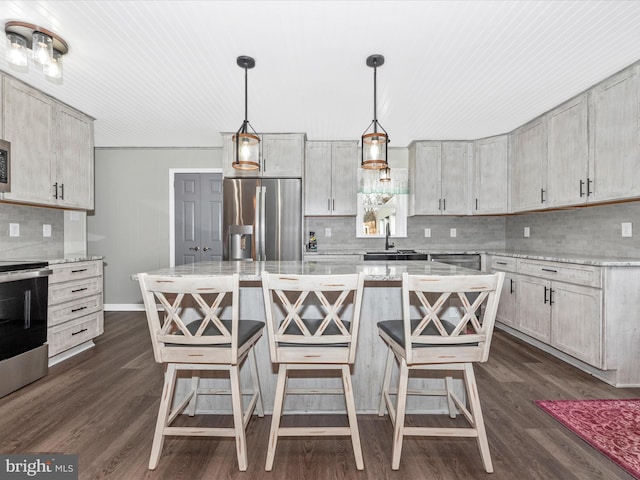 kitchen with a kitchen island, pendant lighting, stainless steel appliances, and a kitchen breakfast bar