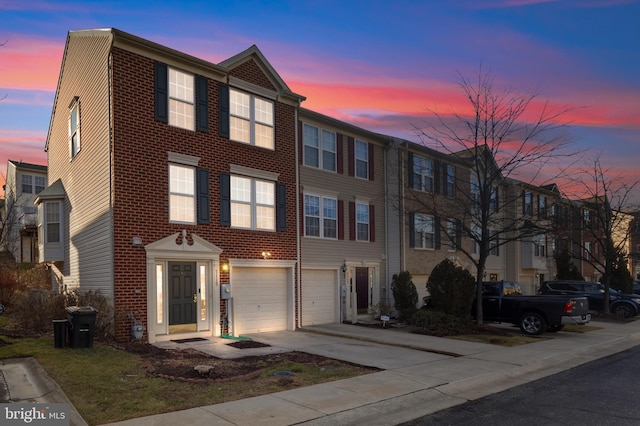 townhome / multi-family property featuring a garage, driveway, and brick siding