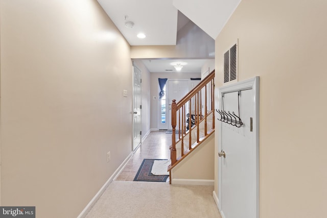 hallway with light colored carpet, visible vents, baseboards, and stairs