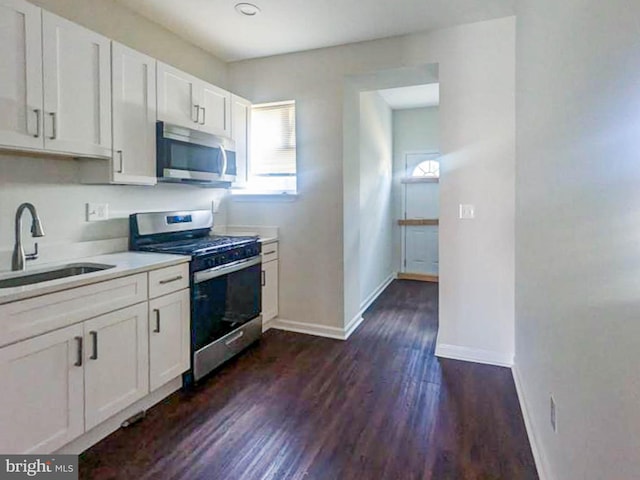 kitchen featuring appliances with stainless steel finishes, dark hardwood / wood-style floors, sink, and white cabinets