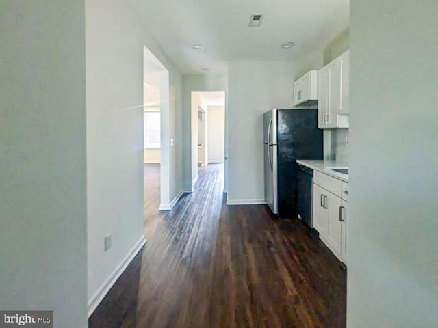 kitchen featuring white cabinetry, dark hardwood / wood-style floors, stainless steel refrigerator, and dishwasher