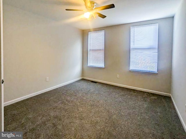 spare room with ceiling fan and dark carpet