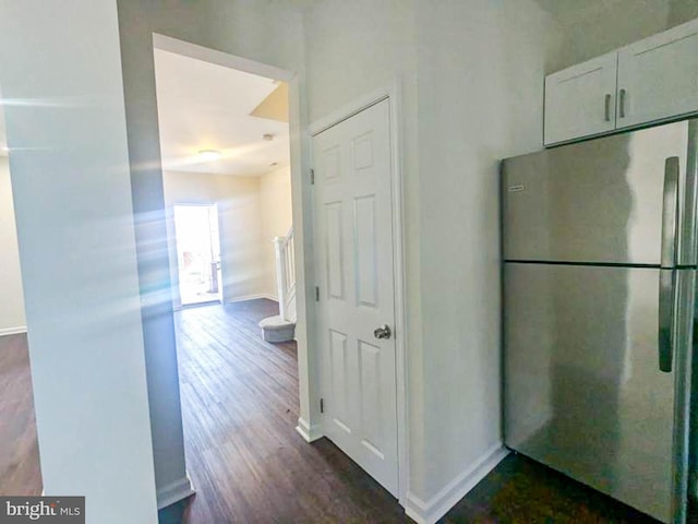 interior space featuring stainless steel fridge, dark hardwood / wood-style flooring, and white cabinets