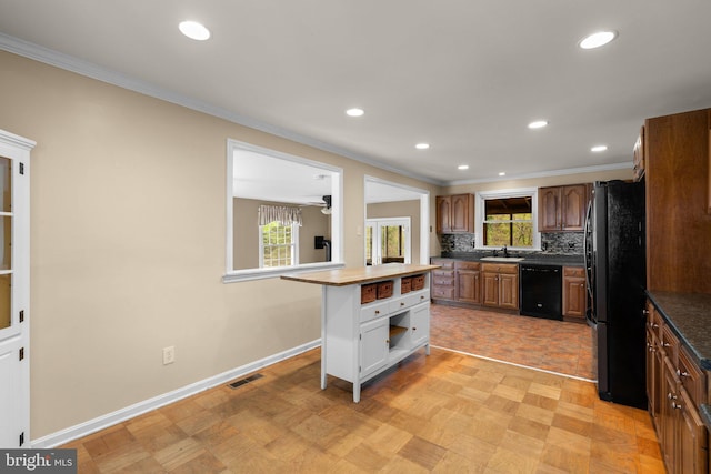 kitchen featuring crown molding, a sink, black appliances, baseboards, and visible vents