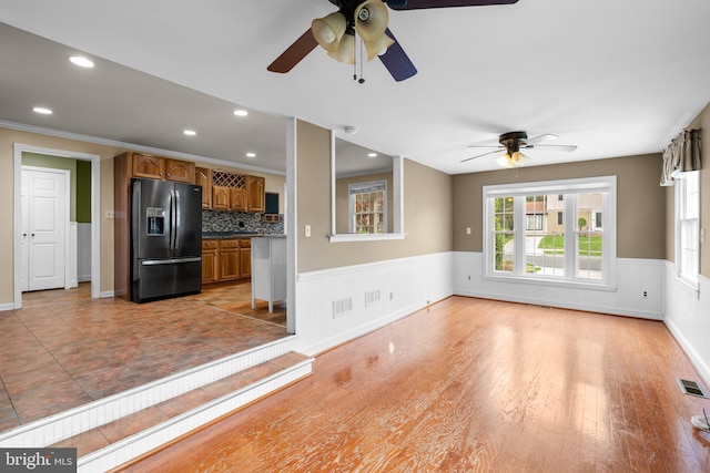 unfurnished living room featuring wainscoting, a ceiling fan, visible vents, and recessed lighting