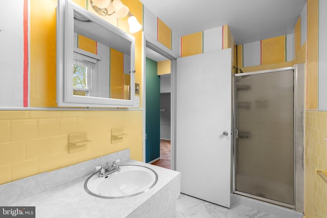 bathroom featuring a shower stall, vanity, and tile walls