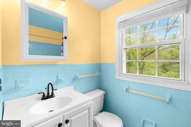 bathroom featuring tile walls, wainscoting, vanity, and toilet