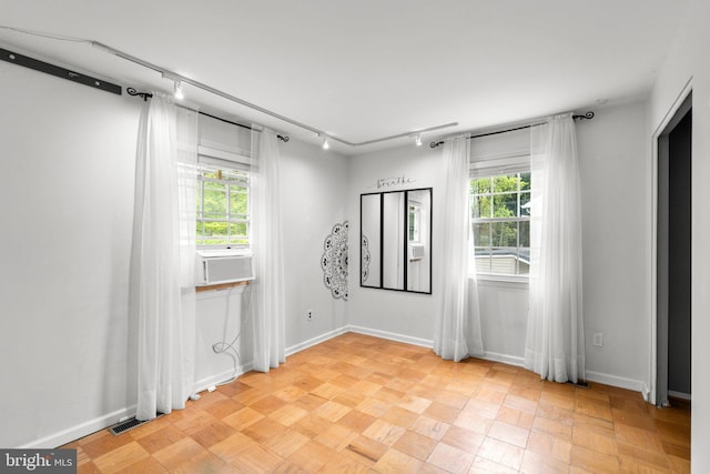 spare room with track lighting and baseboards