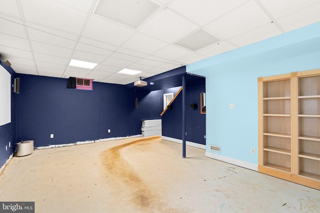finished below grade area featuring baseboards, visible vents, stairs, and a drop ceiling