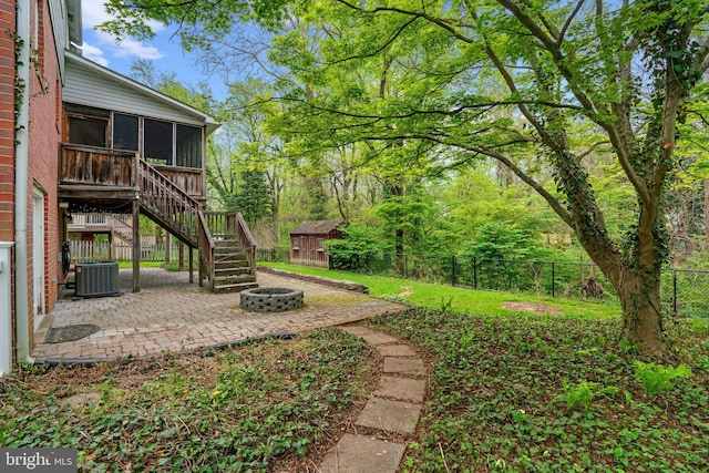 view of yard featuring a patio area, a storage shed, a fire pit, a sunroom, and stairs