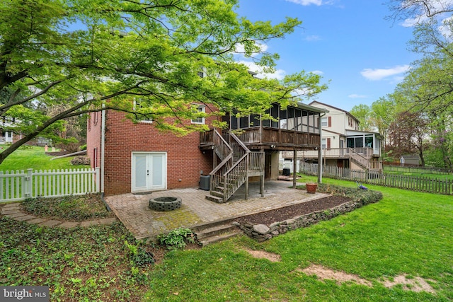rear view of property with a fire pit, a patio area, a sunroom, and stairs