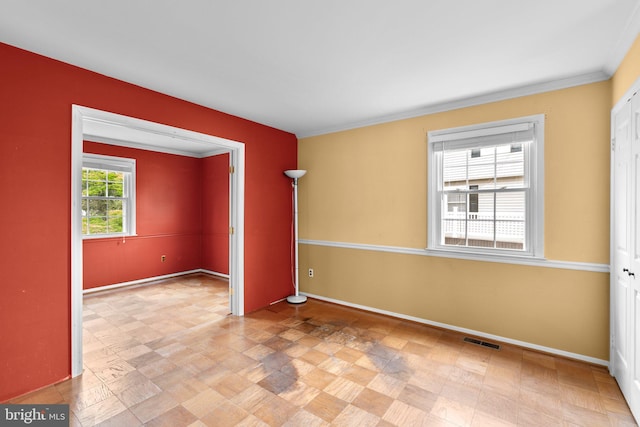 unfurnished room with visible vents, crown molding, and baseboards