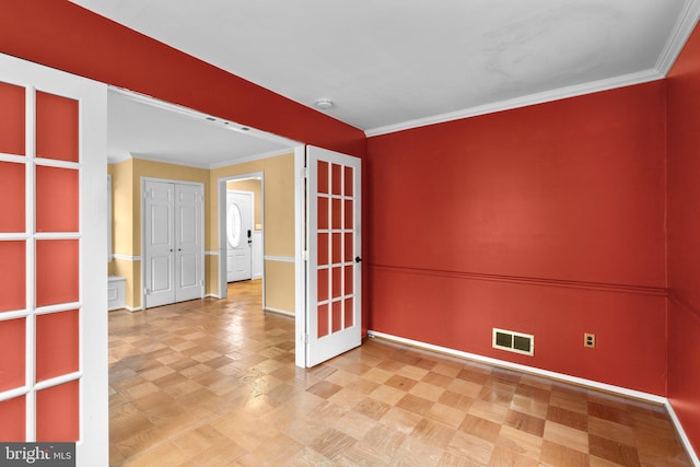 empty room featuring visible vents, baseboards, ornamental molding, and french doors