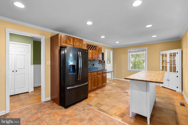 kitchen featuring brown cabinets, visible vents, black fridge with ice dispenser, and ornamental molding