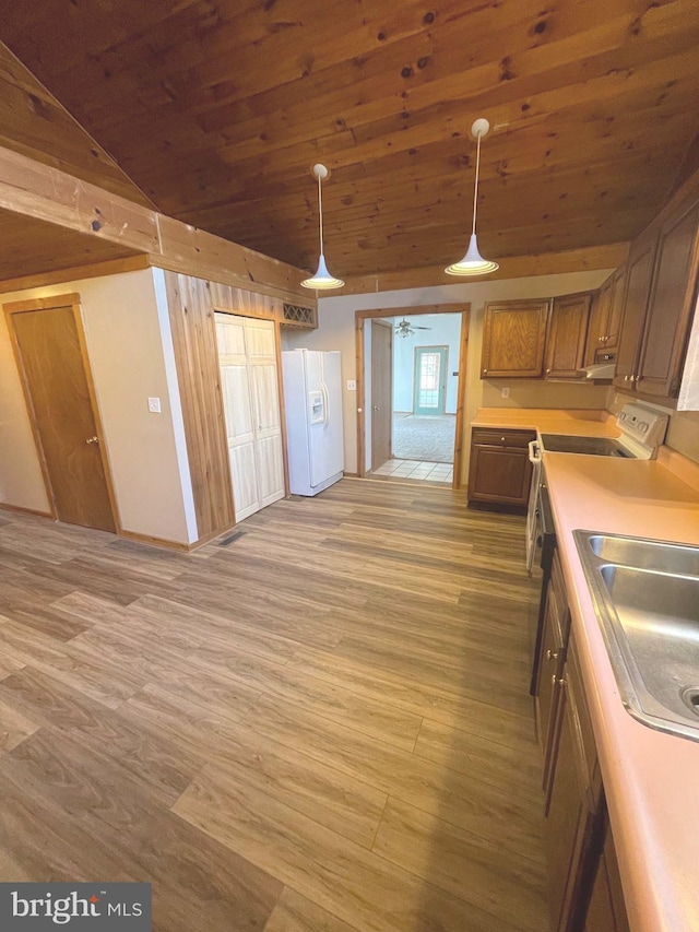 kitchen featuring wood-type flooring, lofted ceiling, white fridge with ice dispenser, and pendant lighting