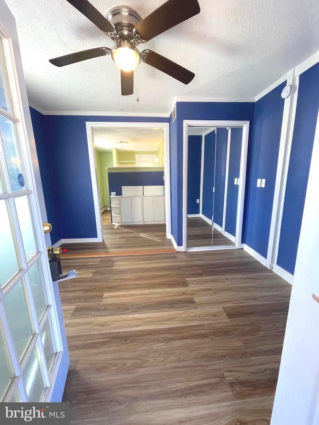 interior space featuring ornamental molding, dark hardwood / wood-style floors, and a textured ceiling