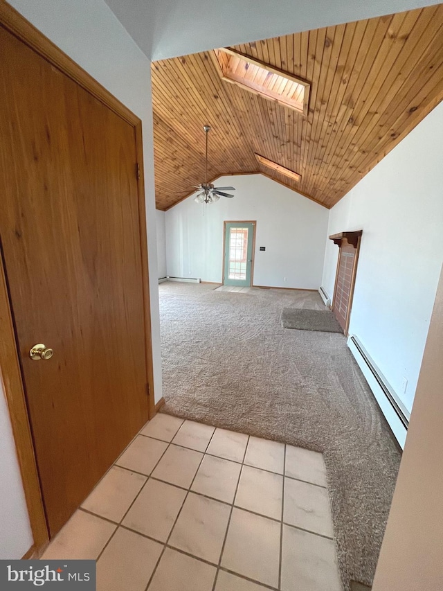 additional living space featuring wood ceiling, baseboard heating, ceiling fan, light colored carpet, and vaulted ceiling with skylight