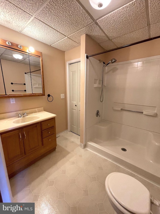 bathroom with vanity, toilet, a paneled ceiling, and walk in shower