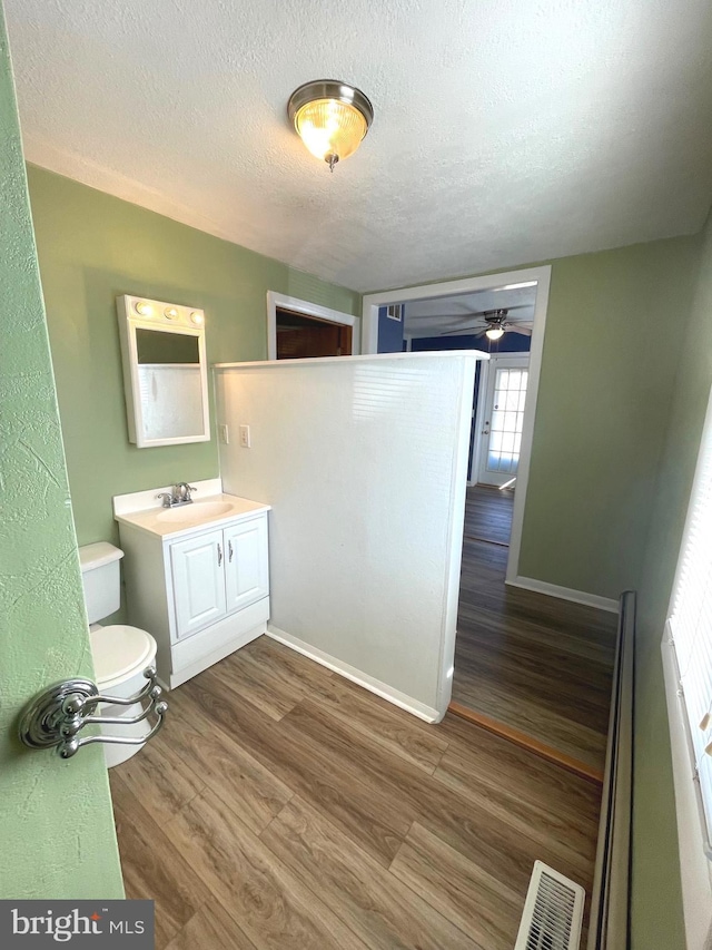 bathroom featuring vanity, toilet, hardwood / wood-style floors, and a textured ceiling