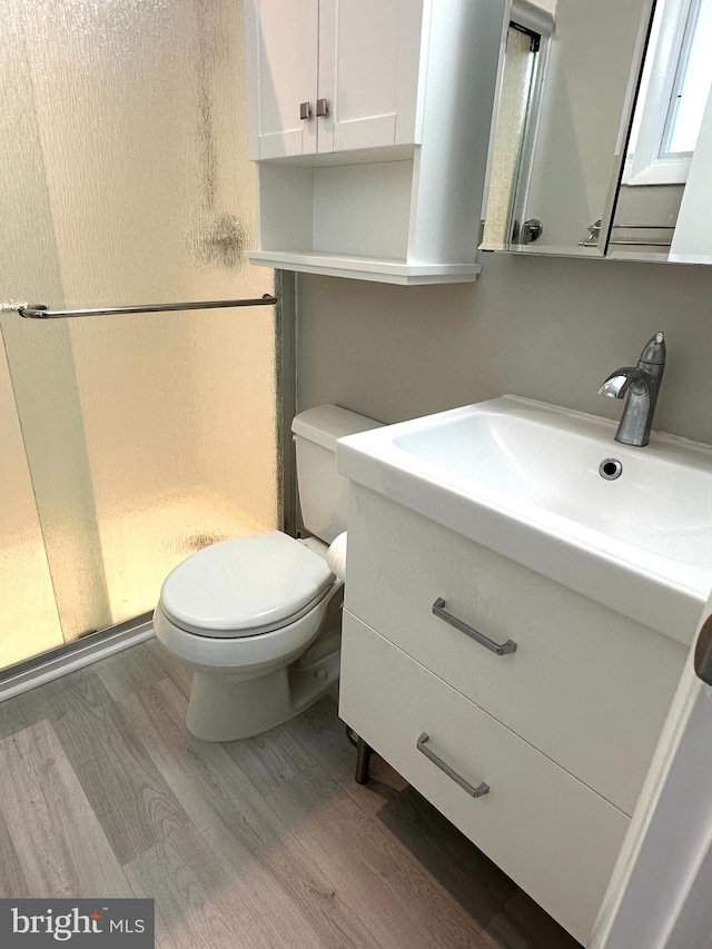 bathroom featuring a shower, hardwood / wood-style floors, vanity, and toilet