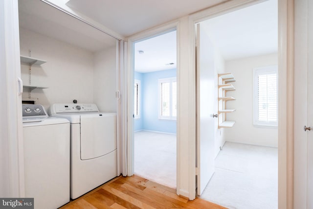 clothes washing area with washer and dryer and light hardwood / wood-style flooring