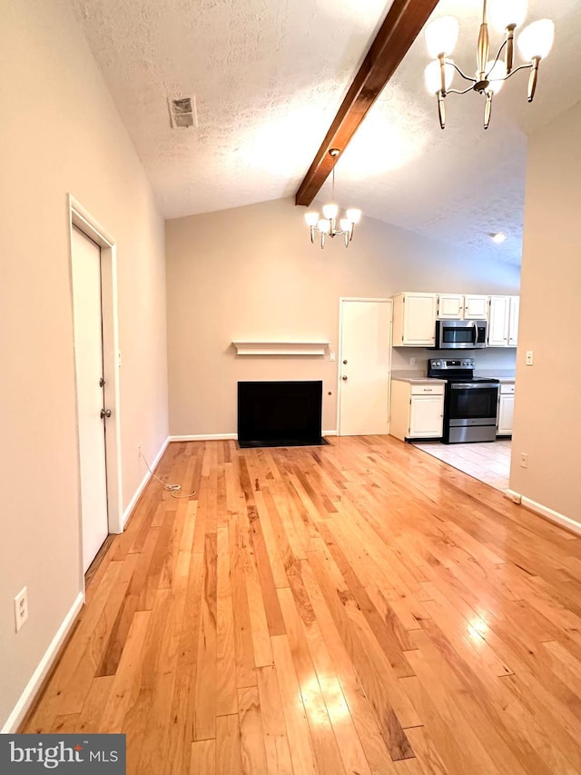 unfurnished living room with an inviting chandelier, light hardwood / wood-style floors, a textured ceiling, and vaulted ceiling with beams