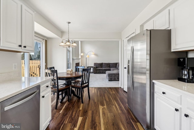 kitchen with appliances with stainless steel finishes, light stone counters, pendant lighting, dark wood-type flooring, and white cabinets