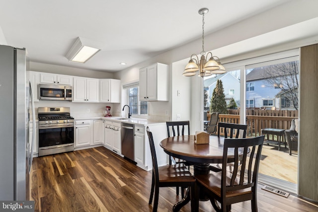 kitchen featuring appliances with stainless steel finishes, pendant lighting, dark hardwood / wood-style floors, and white cabinets