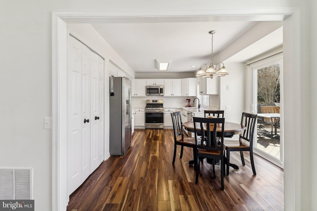 dining room featuring sink, dark hardwood / wood-style floors, and a notable chandelier