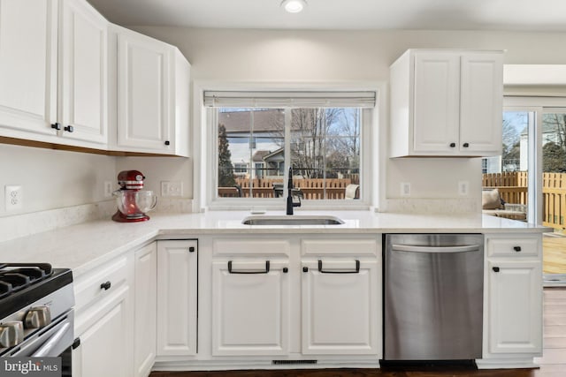 kitchen with appliances with stainless steel finishes, sink, white cabinetry, and light stone countertops