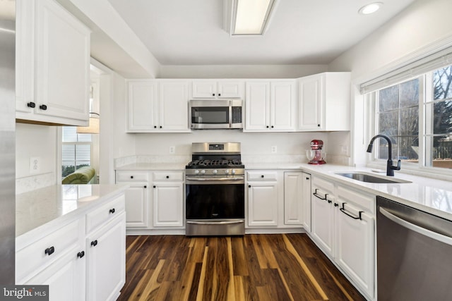 kitchen with appliances with stainless steel finishes, white cabinets, sink, dark hardwood / wood-style floors, and a healthy amount of sunlight