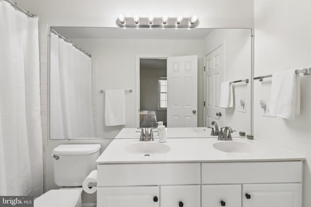 bathroom featuring toilet, vanity, and a shower with curtain