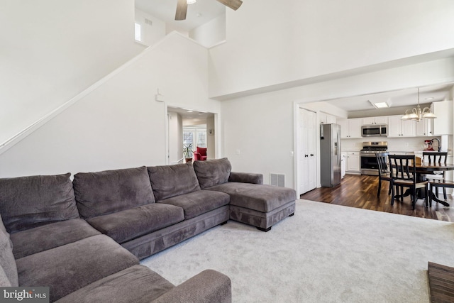 living room featuring ceiling fan with notable chandelier, a high ceiling, and dark hardwood / wood-style floors