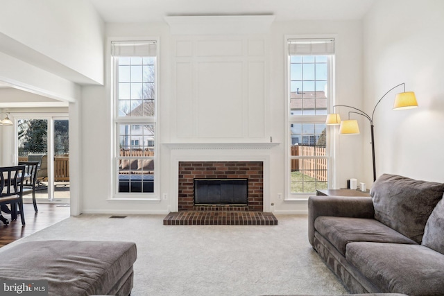 carpeted living room with a high ceiling, a brick fireplace, and plenty of natural light