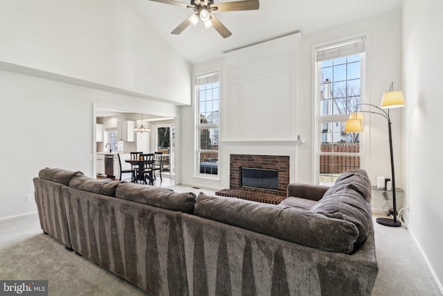 carpeted living room featuring a fireplace, high vaulted ceiling, and ceiling fan