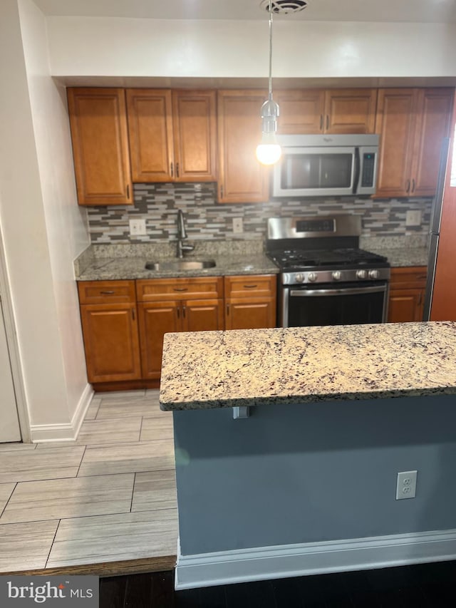 kitchen with light stone countertops, appliances with stainless steel finishes, sink, and decorative backsplash