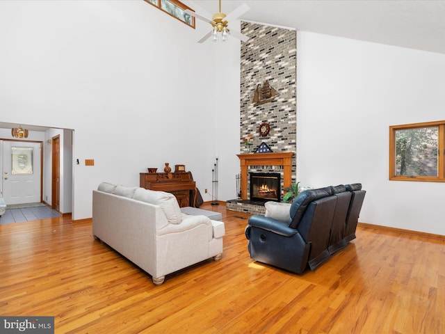 living room with a brick fireplace, light hardwood / wood-style floors, and a high ceiling