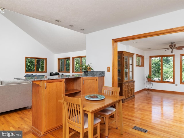 dining room featuring lofted ceiling, ceiling fan, light hardwood / wood-style floors, and a textured ceiling