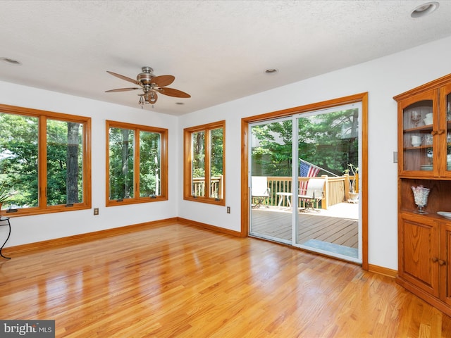 interior space featuring ceiling fan, light hardwood / wood-style flooring, a textured ceiling, and plenty of natural light