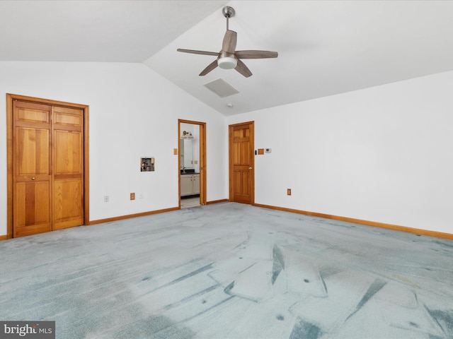 unfurnished bedroom with ceiling fan, light colored carpet, ensuite bathroom, and vaulted ceiling