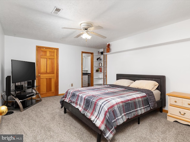 carpeted bedroom with ceiling fan and a textured ceiling