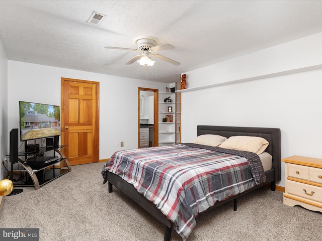 bedroom featuring ceiling fan, light colored carpet, and a textured ceiling