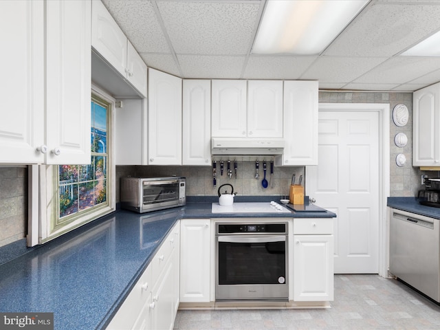 kitchen with white cabinetry, appliances with stainless steel finishes, decorative backsplash, and a drop ceiling