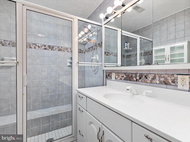 bathroom with walk in shower, tasteful backsplash, a textured ceiling, tile walls, and vanity