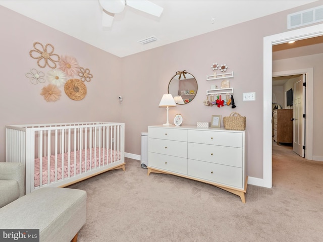 carpeted bedroom featuring a nursery area and ceiling fan