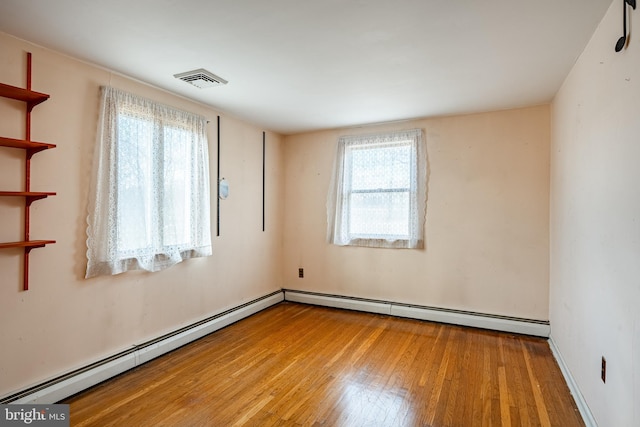 empty room featuring a baseboard heating unit and light wood-type flooring