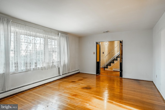 spare room featuring wood-type flooring and baseboard heating