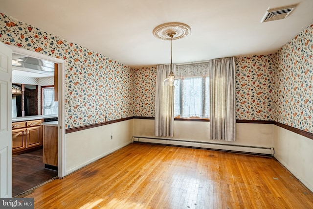 unfurnished dining area with light wood-type flooring and baseboard heating